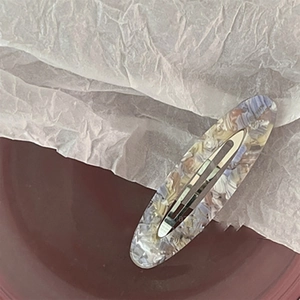 Close-up of vintage hollow oval acetate hair clip with colorful marble pattern