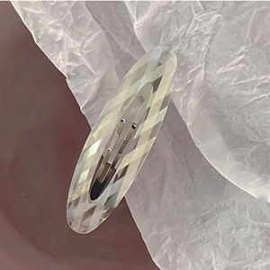 Detail view of the diamond-cut faceted oval acetate hair clip on a minimalist background