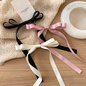 Barrettes à nœuds en satin rose, noir et crème avec longs rubans sur fond en bois minimaliste