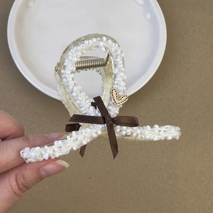 Dettaglio del ricamo in perle su un fermaglio per capelli con fiocco marrone e cuore