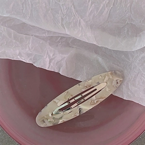 Close-up of marble pattern acetate oval hair clip on decorative plate