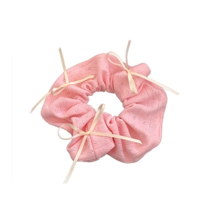 Pink knit scrunchie with pointelle texture and delicate white ribbon bow decorations