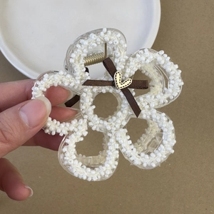 Dettaglio molletta per capelli con fiocco marrone, perle bianche e cuore dorato