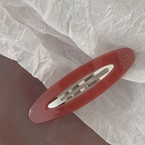 Detailed macro view of an oval burgundy acetate hair clip with Barrette La France lettering
