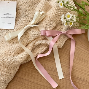 Barrettes à nœuds en satin rose et ivoire sur un fond en maille beige texturé