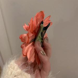 Elegant floral hair claw featuring realistic orange pink silk camellia petals and green leaves