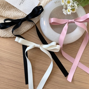 Détail de barrettes à nœuds en satin rose, blanc et noir avec texture de soie douce