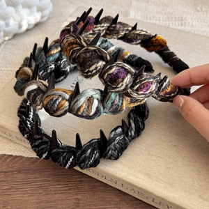 Hand-woven wool headband with spikes and non-slip teeth, displayed on a vintage book