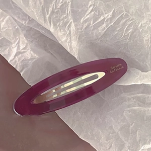 Macro view of a deep purple acetate oval hair clip with an elegant hollow center