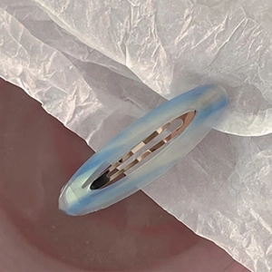 Detailed close-up of blue oval marble acetate hair clip with metal spring mechanism