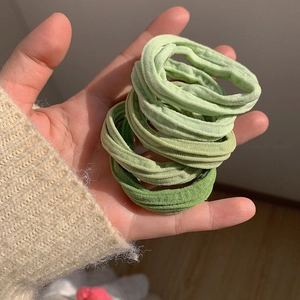 Gros plan détaillé des chouchous macaron verts à haute élasticité tenus dans la main