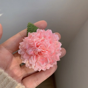 Détail de la pince à cheveux fleur de chrysanthème en tissu rose avec feuille verte