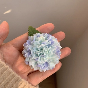 Détail de la pince fleur en tissu bleu et violet avec petite feuille verte