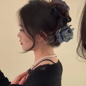 Pince à cheveux fleur rose en tissu bleu élégante portée par un mannequin femme