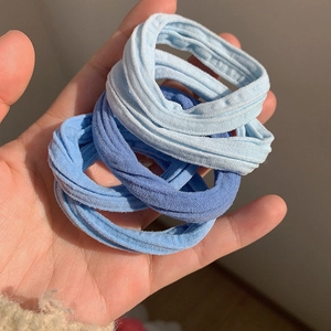 Détail d'élastiques à cheveux bleu macaron haute élasticité tenus à la main pour l'échelle