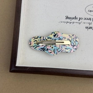 Detailed close-up of cloud-shaped acetate hair clip with iridescent marble texture finish
