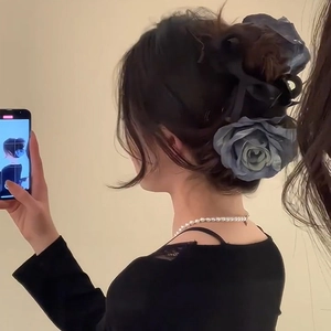 Détail d'une pince à cheveux rose en soie bleu poudré vintage sur un chignon élégant