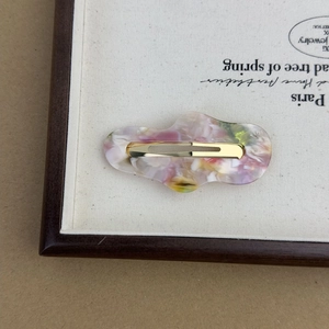 Detail of acetate cloud pattern hair clip with gold metal clasp on a canvas tray