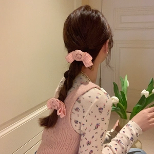 Close-up of pink camellia bow hair clips with textured fabric on a braided hairstyle