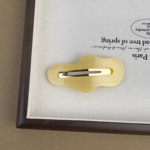 Detailed view of yellow acetic acid cloud hair clip with irregular wave design and metal grip