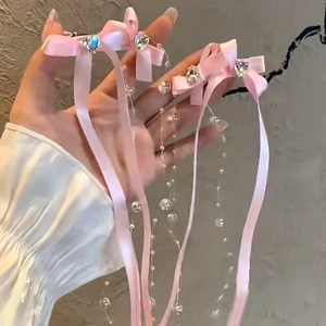 Détail de nœuds en ruban rose avec pampilles de perles et strass en forme de cœur