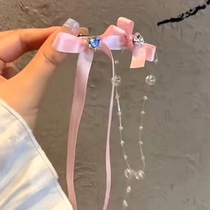 Détail de la barrette nœud en soie rose avec cœurs sertis et longs glands perlés