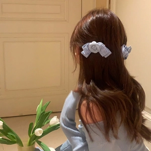 Elegant light blue tweed bow hair clips with camellia flowers shown on brown wavy hair