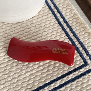 Dettaglio del fermaglio per capelli rosso ondulato con scritta dorata France Handmade