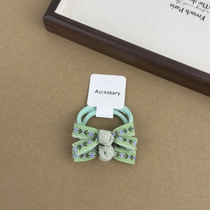 Detail view of two light green floral print fabric bow hair ties on a display card
