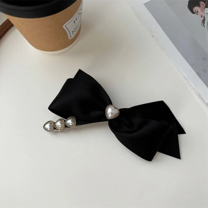 Elegante fermaglio per capelli in raso nero con perle a cuore su sfondo alla moda