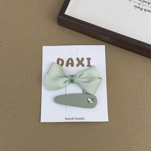 Detail view of handmade green floral bow hair clips and fabric hairpins on display card
