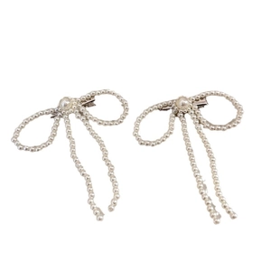 Elegant pair of pearl bow hair clips with white faux pearls on a minimalist background