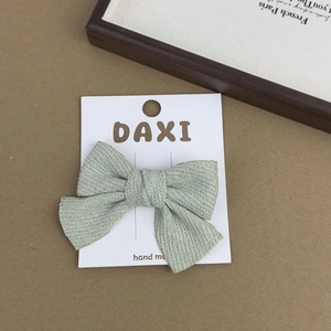 Close-up of light green floral fabric bow hair clip on a handmade retail card package