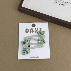 Detail of mint green floral bow hair clips with knitted texture on display card