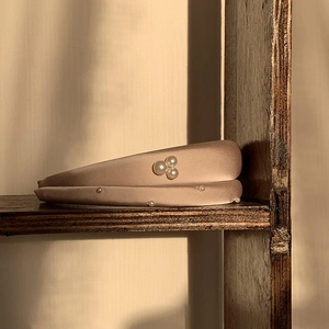 Rosa gepolstertes Satin-Haarband mit Perlen auf einem Vintage-Holzregal präsentiert