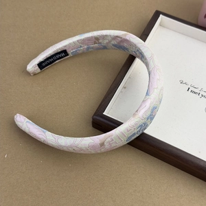 Detailed close-up of pink and blue jacquard fabric headband with handmade label