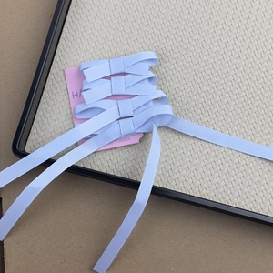 Set of four light blue ribbon bow hair clips with long tails on pink display card