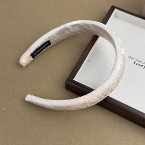 Close-up of handmade cream jacquard satin headband with pink floral patterns