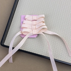 Detailed macro view of four nude pink ribbon bow hair clips on a display card