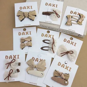 Handmade striped bow hair clip set in beige and brown tones on display card