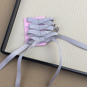 Detailed view of four dusty purple ribbon bows on a pink display card set on a tray