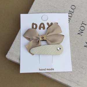 Detail of handmade khaki bow hair clip and striped BB clip set on display card