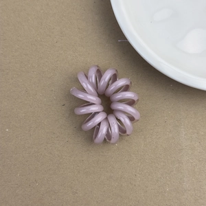 Élastique à cheveux spirale violet pastel en résine sur fond texturé vintage