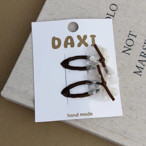 Detail of dark brown fabric hair clips with lace mesh and sequins on white card