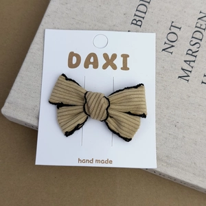Close-up of handmade ribbed brown fabric bow hair clip with elegant black stitched edges