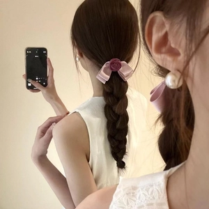Pink satin bow hair tie with purple rose and elegant pearl earrings on a female model
