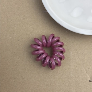 Gros plan d'un chouchou spirale violet style cordon de téléphone sur fond minimaliste