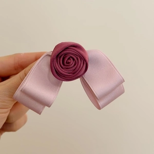 Detailed texture of handmade raspberry pink satin rose and ribbon bow hair clip