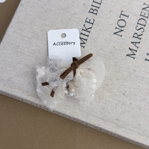 Detail of white lace hair tie with sequins on display card against brown background