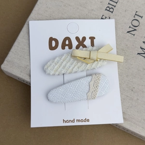 Detail of handmade bow hair clips set with striped fabric and lace on a display card